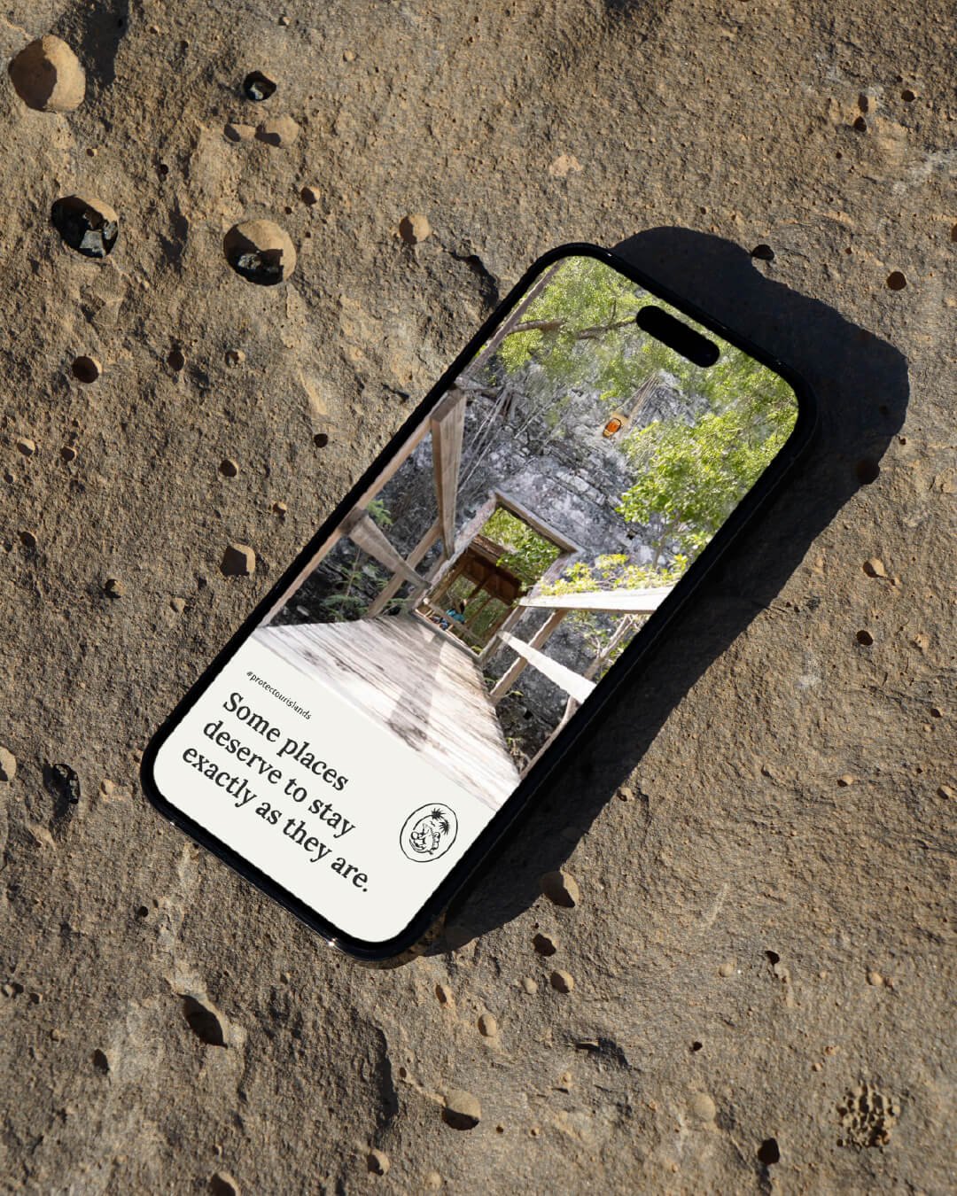 Smartphone on a rocky surface displaying the message: Some places deserve to stay exactly as they are. #protectourislands